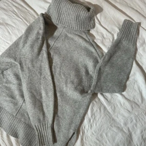 Grå polotröja från hm - Mysig grå polotröja med bred ribbad krage och muddar. Tröjan är stickad och har lång ärm, perfekt för kyliga dagar. Enkel och stilren design som passar till det mesta.