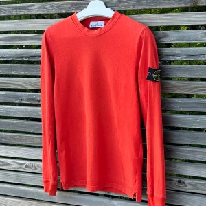 Röd långärmad tröja från Stone Island - Säljer en röd stickad tröja från Stone Island med klassisk patch på ärmen och är lite tunnare. Tröjan har rund halsringning, sicket är perfekt och en 9/10 