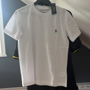 Vit t-shirt från Polo Ralph Lauren - Fräsch vit t-shirt från Polo Ralph Lauren med klassisk rund hals och korta ärmar. Diskret logga broderad på bröstet. Perfekt basic-plagg med snygg passform och mjukt bomullsmaterial.