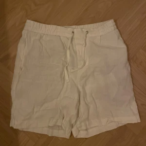 Vita linneshorts och ett par linnebyxor - Säljer ett par fräscha vita shorts i linne med elastisk midja och snörning framtill. Dessutom säljer jag ett par linnebyxor. 