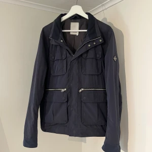 J.Lindeberg field jacka mörkblå  - Säljer denna sjukt snygga field jackan från J.Lindeberg⭐️ Färgen är mörkblå och storleken är L✅ Jackan har inga defekter och skicket är utomordentligt🙌🤝 Sjukt najs passform och passar perfekt till hösten🍁🙌 Tveka inte på att höra av er dig vid minsta fråga eller fundering😊