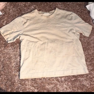 Beige basic t-shirt i bomull - Enkel beige t-shirt med rund hals och korta ärmar. Skön och avslappnad passform, perfekt till jeans eller shorts. Tillverkad i mjuk bomull som andas. Stilren och lättmatchad för en clean look.