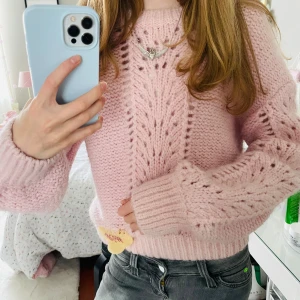 Ljusrosa stickad tröja från & Other Stories - Säljer jättefin ljusrosa stickad tröja från & Other Stories med snyggt hålmönster framtill och på ärmarna. Tröjan har rund hals och ribbade muddar.