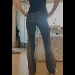 Vintage lågmidjade bootcut jeans - Säljer ett par blågrå Lågmidjade bootcut jeans med bruna breda ränder på sidorna. Jag har köpt dom på en secondhand i Stockholm! Dom är små slitna vid hällarna men annars topp skick.🥲🤩