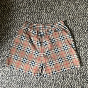 Burberry badshorts – Helt nya, storlek M - Beskrivning: Säljer ett par helt nya Burberry badshorts i klassiskt rutmönster. Aldrig använda, med innernät och etikett kvar. Storlek M. Väldigt bra kvalitet och tillverkade i Portugal, 100% bomull. Passar perfekt till sommaren eller semestern! Pris: Pris kan diskuteras – kom med bud!