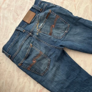 Nudie jeans grim Tim - Säljer ett par grim Tim från från Nudie Jeans mycket eftertraktad model med slitningar och feta fades. Klassiska bakfickor, jeansen har en reparation ovanför bakfickan, Jeansen har slim passform och är tillverkade i mjukt denimtyg. Båda framfickorna har hål i sig på insidan men annars mycket feta jeans, passar kring 180-185