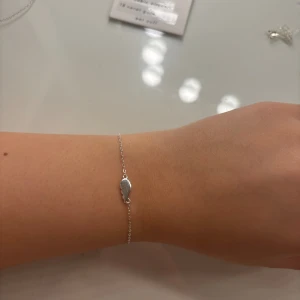 Tunt silverarmband med ett halvt hjärta - Superfint och minimalistiskt armband i silverfärg med en liten, droppformad berlock på en tunn kedja. Perfekt för dig som gillar diskreta smycken med en unik detalj. Passar snyggt både ensam eller i kombination med andra armband.