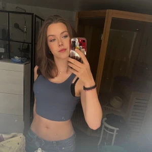 Blå croppad linnetopp - Säljer en stilren blå croppad linnetopp med breda axelband och rund halsringning. Toppen är ärmlös och har en enkel, slät design som är perfekt för varma dagar. Materialet känns mjukt och stretchigt mot huden. Storleken är egentligen XS, men tyget är stretchigt och passar även S.