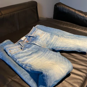 Blåa jeans Jack & Jones Comfort Mike - Säljer ett par blåa jeans från Jack & Jones, modell Comfort/Mike. Jeansen har klassisk femficksdesign, ljus tvätt med snygga slitningar och kontrastsömmar. De är raka i modellen och tillverkade i mjukt bomullstyg för extra komfort.