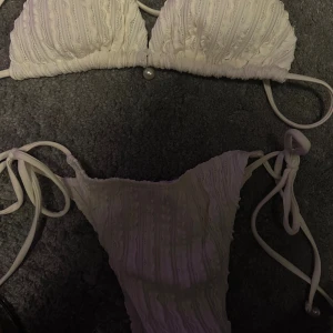 Vit bikini med pärldetaljer och snörning - Superfin vit bikini med ribbad struktur och snygga pärldetaljer på både över- och underdel. Bikinin har knyt i sidorna och på ryggen för perfekt passform. Perfekt för stranden eller poolen i sommar!