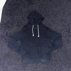 Mörkblå hoodie från Pier One - Snygg mörkblå hoodie från Pier One med vit snörning i huvan och klassisk känguruficka framtill. Tröjan har långa ärmar och är tillverkad i mjuk bomull, perfekt för chill dagar eller när du vill ha en enkel och stilren look.