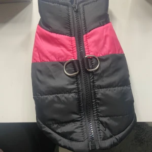 Svart och rosa jacka för hund - Säljer en vinterjacka för hund i svart och rosa med quiltad design. Västen har en dragkedja på ryggen och två metallringar för koppel. Storlek 20 i rygglängd