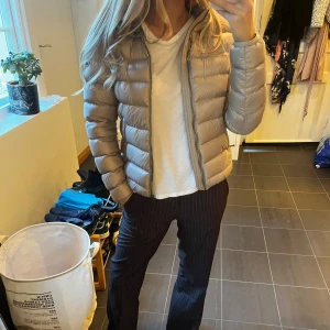 Beige dunjacka från Colmar med huva - Säljer min snygg beigea dunjacka från Colmar med huva och dragkedja framtill. Jackan är quiltad och har en glansig finish. Perfekt för kyliga dagar och har en normal passform. Colmar-logga på ärmen. Nypris 5500 kr