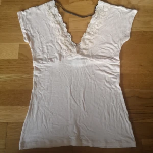 Ljusrosa spetsdetaljerad topp från Zara - Supersöt ljusrosa topp från Zara Collection med djup v-ringning och breda spetsdetaljer längs halsringningen och i ryggen. Mjukt material med korta ärmar och feminin passform. Perfekt festtopp men funkar även till vardag. Skriv vid frågor💞