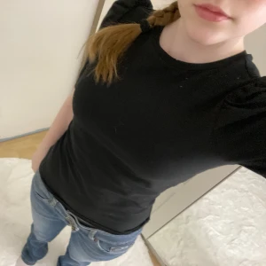 Svart topp med puffärm från ONLY - En svart, figurnära topp från ONLY med korta puffärmar och rund halsringning. Toppens material är mjukt och stretchigt, vilket gör den bekväm att bära. Enkel men ändå trendig design som passar perfekt till jeans eller kjol. 🩷 Köpte den fast jag aldrig använde den (därför prislappen är kvar) 💗 (Ordinarie pris 229.95kr) 