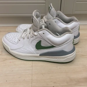 Nike Air Jordan 2 Low vit/grön - Säljer ett par Nike Air Jordan 2 Low i vitt och grönt med grå detaljer. Skorna har klassisk snörning, perforerad tå och gröna Nike-loggor samt gul Jumpman på sulan. Ovandelen är i skinn och sula i gummi. Perfekt för dig som gillar retro sneakers med coola färgdetaljer.