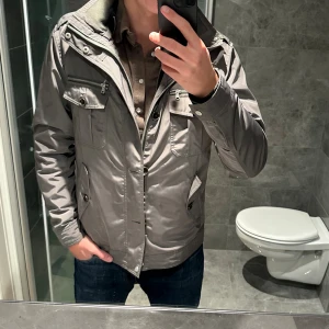 Olivgrön Fieldjacket  - Säljer en olivgrön/ljusgrön field jacket från märket Riley. Obs färgen är lite missvisande gentemot vilken färg den är i verkligheten. På bilderna ser den grå ut men den är egentligen grön (se sista bild) Jackan är i riktigt bra skick och är i princip helt oanvänd. Jag är 188cm och bär storlek 50 vilket motsvarar en M. Hör av er vid funderingar eller fler bilder på jackan;)