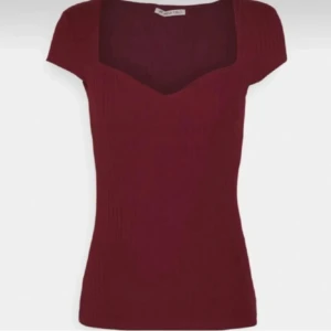 Vinröd ribbad topp med sweetheart-ringning - Vinröd ribbad topp från NA-KD med korta ärmar och snygg sweetheart-ringning. Toppen är figurnära och har en stilren, enkel design som passar perfekt till jeans eller kjol. Materialet är stretchigt och bekvämt.