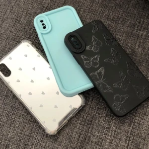 iPhone X/XS skal, 3-pack - Säljer tre snygga iPhone X/XS skal: ett svart med fjärilar, ett spegelblankt med hjärtan och ett ljusblått silikon. Alla är oanvända nya