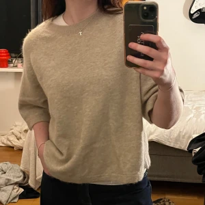 Beige stickad tröja & Other Stories - Beige stickad tröja från & Other Stories med halvkort ärm. Tröjan är mjuk och bekväm. Storlek M men passar även S