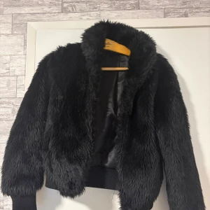 Svart pälsjacka från JC XS - Säljer en svart pälsjacka från JC i storlek XS. Jackan har fluffig och mjuk yta med långärmade ärmar och ribbade muddar. Insidan är fodrad med glansigt tyg som känns lyxigt. Perfekt för dig som vill ha en cool och trendig look.