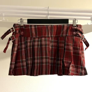 Rutig röd minikjol med spännen - Kort rutig kjol med snygga spänndetaljer i midjan, perfekt för dig som gillar Y2K, punk eller trendig streetstyle. Aldrig använd och i toppskick, Liten i storlek  📍 Endast upphämtning i centrala Jönköping  #y2kstyle #minikjol #tartankjol #trendigtmode #secondhandfashion #luminaox #jönköping