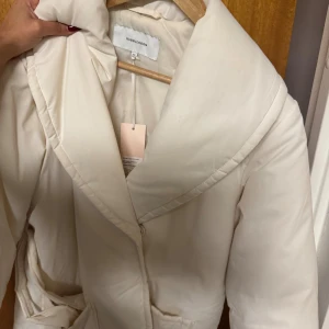 Vit pufferjacka från Bubbleroom - Snygg vit pufferjacka från Bubbleroom med bred krage och bälte i midjan. Helt ny jacka 