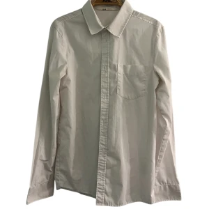 Vit skjorta från H&M med ficka - Klassisk vit skjorta från H&M med lång ärm och bröstficka. Skjortan har en rak passform, knappar framtill och är tillverkad i bomull.