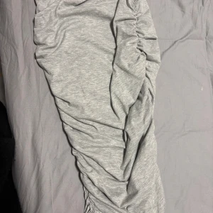 Grå ruched kjol från SHEIN - Snygg grå kjol från SHEIN med ruched detaljer längs sidorna som ger en cool och trendig look. Kjolen har elastisk midja och är tillverkad i mjukt, stretchigt material som känns bekvämt hela dagen. (Aldrig använt) köpte den och en svart, den svarta gick till användning men tyvärr inte den gråa, priset kan diskuteras.