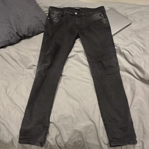Replay Jeans - Svarta jeans från Replay med skinny passform och klassisk femficksdesign. Jeansen har svarta sömmar, Replay-logga på fickan och metallknappar. Materialet är stretchigt jeans för en tajt och bekväm känsla. Perfekt för dig som gillar en stilren och modern look.