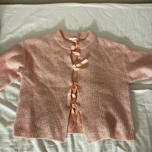 Rosa kofta med rosetter från Gina Tricot - Supersöt ljusrosa stickad kofta från Gina Tricot med tre fina rosetter framtill istället för knappar. 