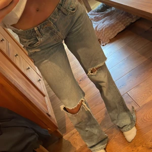 Ljusblå slitna jeans med raka ben - Säljer dem populära jeansen från Zara med slitningar och hål. Bra skick förutom kanten vid fötterna så dem är slitna!❤️ 