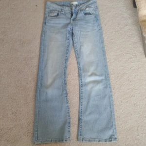 Ljusblå bootcut jeans med fickdetaljer -  Ljusblå jeans från Gina Tricot med bootcut passform och klassiska fem fickor. Jeansen har snygga fickdetaljer med knapp framtill och är tillverkade i mjukt denimtyg. Väl använda, men fortfarande i bra skick.