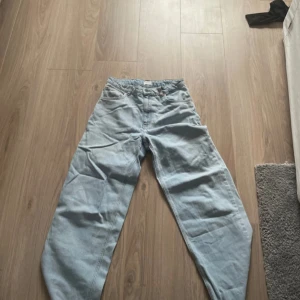 Ljusblå wide jeans från Grunt - Säljer ett par ljusblå jeans från Grunt med breda ben och klassisk femficksdesign. Jeansen har hög midja, raka bakfickor och snygga kontrastsömmar. Perfekt för dig som gillar en avslappnad och trendig look.
