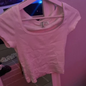 Vit ribbad topp från Divided - Säljer en vit ribbad topp från Divided i storlek XXS. Toppen har korta ärmar, rund halsringning och är gjord i mjuk bomull. Perfekt för dig som gillar enkla och stilrena plagg med en slim passform. Snygg att matcha med jeans eller kjol!