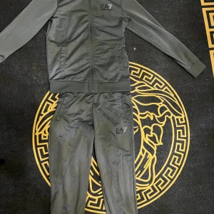 Grå EA7 zipjacka med logga - Grå EA7 kofta och byxa med skön material. Säljer den då den är alldeles för liten.  Kan säljas separat