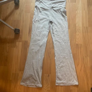 Ljusgrå bootcut yogapants Gina Tricot - Snygga ljusgrå bootcut byxor från Gina Tricot i mjukt och stretchigt material. De har låg midjade men är uppvikta på bilden. Enkel, stilren design utan synliga detaljer. Perfekta för en chill och trendig look. Helt oanvända eftersom att jag inte märkte att dom var för korta. 