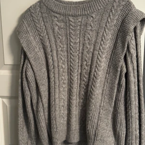 Grå stickad tröja - Säljer en grå stickad tröja. Tröjan har rund halsringning och långa ärmar.