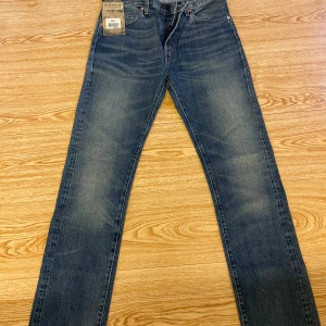 Levi's 505 jeans blå vintage 31/34 - Säljer ett par klassiska Levi's 505 jeans i blå tvätt med vintagekänsla. Modellen har rak passform, normal midja och snygga slitningar framtill. Jeansen är gjorda i 100%.                                                            Midja: 36cm Benlängd:86cm Längd på hela: 115cm Fotvidd: 18,5cm