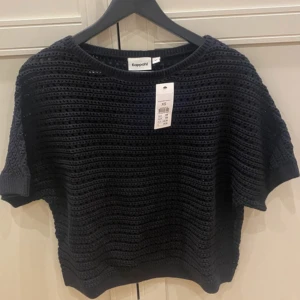 Svart stickad topp från Kappahl - Säljer en svart stickad topp från Kappahl i storlek XS. Toppen har korta ärmar och ett snyggt hålmönster som ger en cool och luftig känsla. Rund halsringning och loose passform gör den enkel att styla. Perfekt för dig som gillar stickade detaljer.