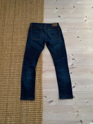 Nudie Jeans Long John mörkblå  - Nudie jeans i w31 asfeta jeans som har en skön fade och några astetiska hål. Kom dm vid funderingar💛