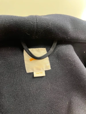 Mörkblå kappa från Gina Tricot - Jag säljer en kort kappa som är förliten. Jag köpte den för 2 år sedan. Den är lite hårig annars har den inga skador eller nått. Jättebra till våren
