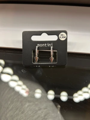 Silvriga örhängen med strass - Coola silvriga örhängen från Montini med strass längs bågen och spetsig konformad detalj längst ner. Helt nya aldrig använda