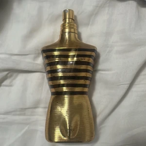 Guldsvart parfymflaska herr - Snygg och unik parfymflaska i guld och svart, formad som en manlig torso. Perfekt för dig som vill sticka ut med din stil. Flaskan är delvis använd, se bild för mängd kvar.