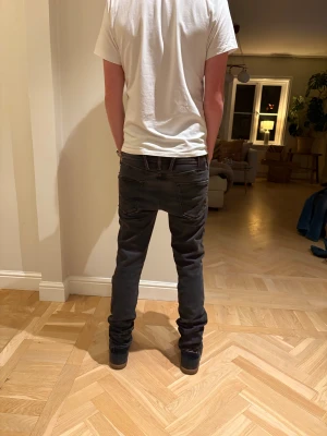 Svarta replay Anbass jeans - Säljer ett par svarta jeans från Replay med slim passform och klassisk femficksdesign. Jeansen har en mörk tvätt, raka ben och snygga detaljer vid fickorna. Materialet är stretchigt jeans för extra komfort och rörelsefrihet.