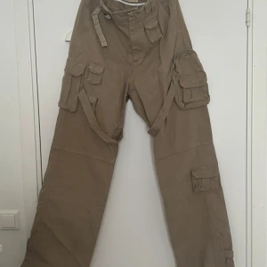 Beiga cargopants från Trendt Vision - Cargopants från Trendt Vision i storlek L. Extra långa i benen som går att knäppa upp. Haft den undanlagd så är i super bra skick, tyvärr har man växt ut storleken den så säljer vidare.