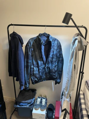 Blå camo Woolrich bomber  - Säljer en blå bomberjacka från Woolrich med camouflagemönster på ena sidan och enfärgad marinblå på andra. Jackan är vändbar, har dragkedja framtill och två fickor. Materialet är lätt och känns syntetiskt, perfekt för vår och höst.