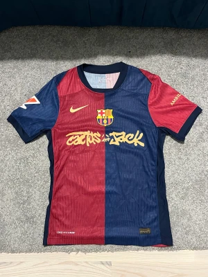 FC Barcelona Lamine Yamal tröja , Travis scott - Säljer en officiell FC Barcelona matchtröja från Nike med Lamine Yamal och nummer 19 på ryggen. Tröjan har klassisk halva röd och halva marinblå design, korta ärmar, gul text och detaljer, samt klubbmärke på bröstet. Materialet är lätt och andas, perfekt för fotboll.
