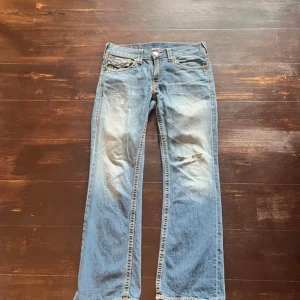 Vintage bootcut True Religion jeans - Riktigt snygga lågmidjade bootcut jeans med schysst wash. Väl använda med täcken på användning vidbotten av byxan (heel bite) Saknar även en knapp vid vänstra fickan på baksidan. Modellen har ett hål på knät kan skicka fler bilder privat så det syns bättre fick inte plats med det här. Hör av er vid minsta fundering🌟