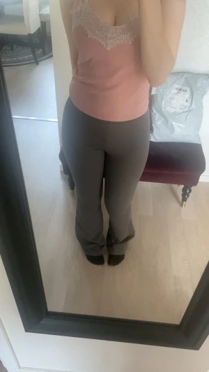 Gråa bootcut byxor med stretch - Snygga gråa bootcut byxor med hög midja och stretchigt material som sitter tajt över höfterna och låren. De har en enkel design utan synliga fickor eller knappar, vilket ger en clean och modern look. Perfekta för dig som gillar bekväma och trendiga byxor.